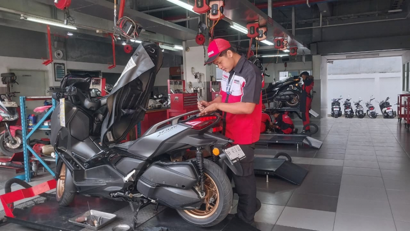 Teknisi Yamaha sedang melakukan perawatan berkala pada motor konsumen 