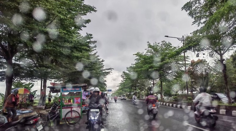 Sejumlah pengendara motor melintas saat hujan ringan